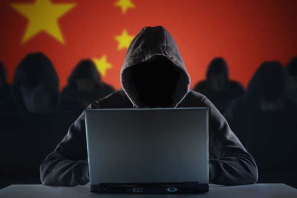 A group of 7 hackers, 6 slightly blurred in the background and one in the foreground, all wearing black with hoods pulled up over their heads. You cannot see their faces.