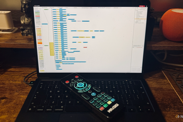 a macbook air showing a complex node red flow with a wi fi remote lying on the keyboard
