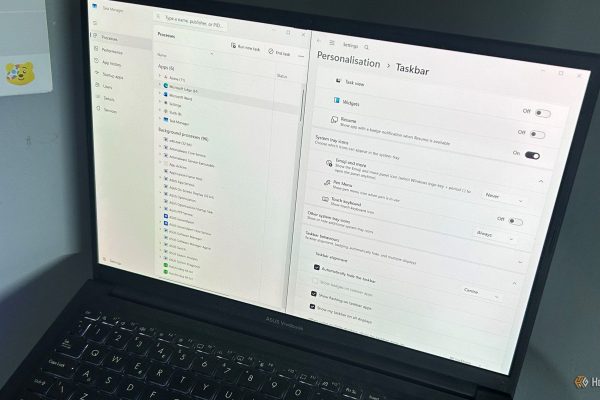 laptop photographed from above with windows 11 task manager and taskbar personalization open side by side