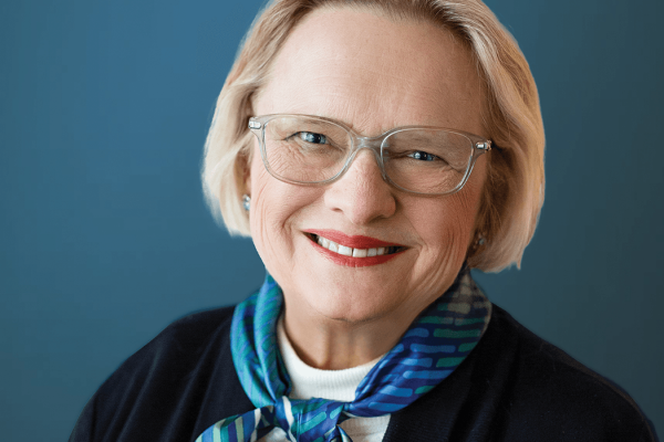 person wearing a scarf over a dark sweater with a blue background