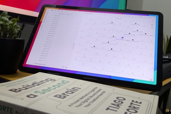 the building a second brain book in front of a table with obsidian graph view open
